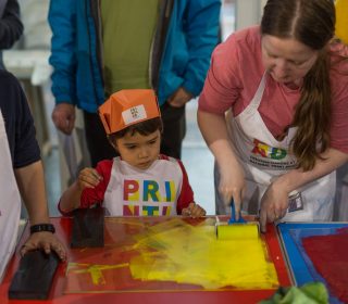 Colourfour PrintLab Children roll yellow ink onto a perspex sheet