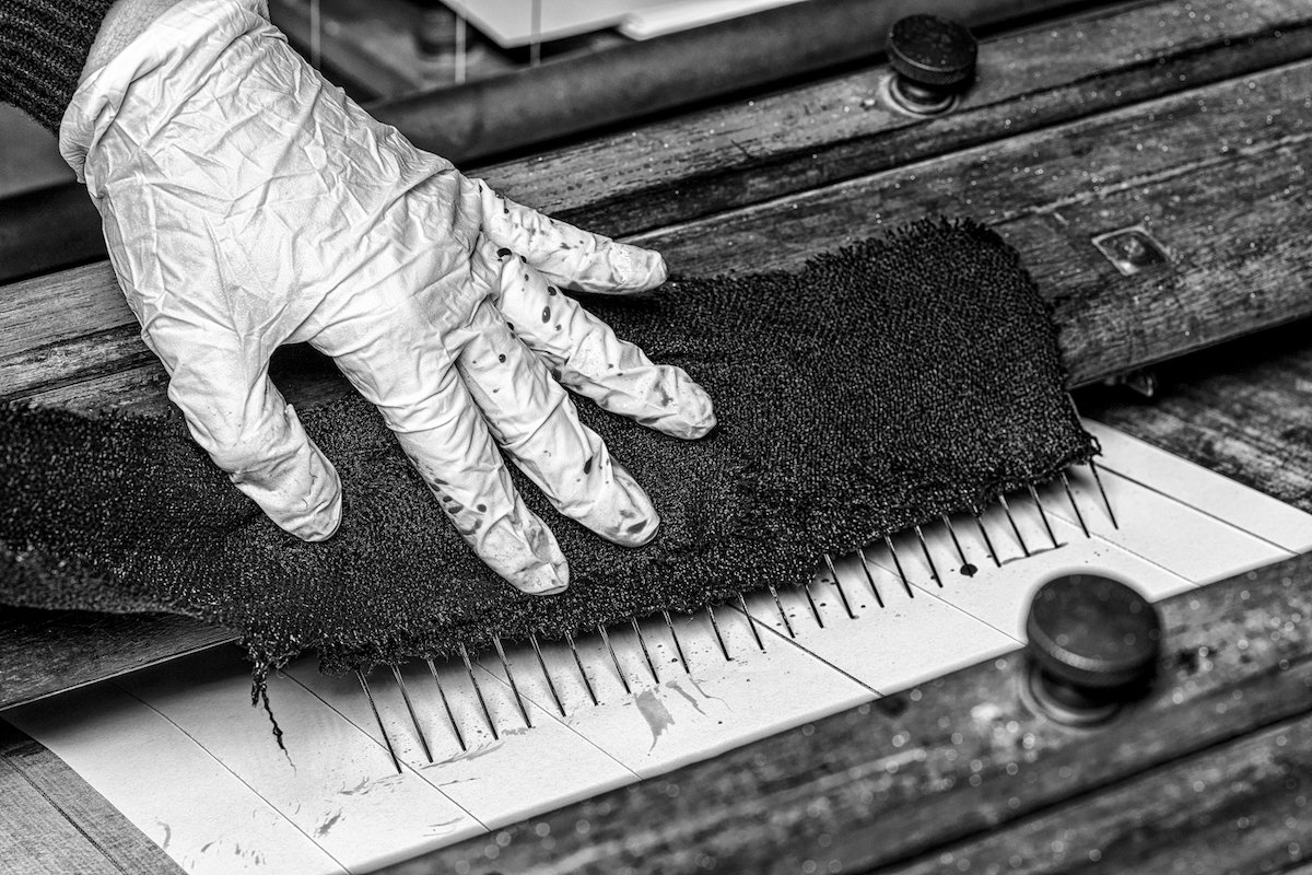 Flannel is held against the pens, which rule lines on paper