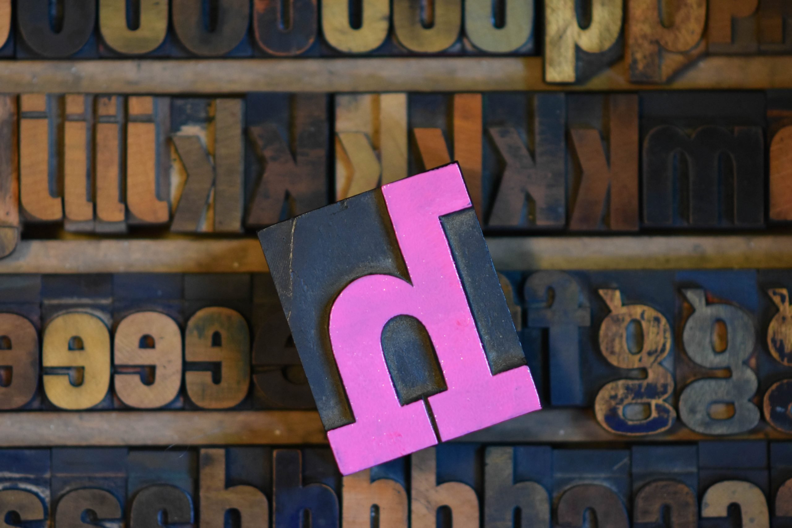 the letter H in wood type, inked in pink