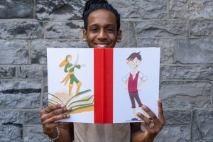 Someone holds open the deluxe edition of 'Blot's Most Marvellous Historical Guide to Printing Books', showing the letterpress-printed illustrations of Blot and Grainne Mhaol.