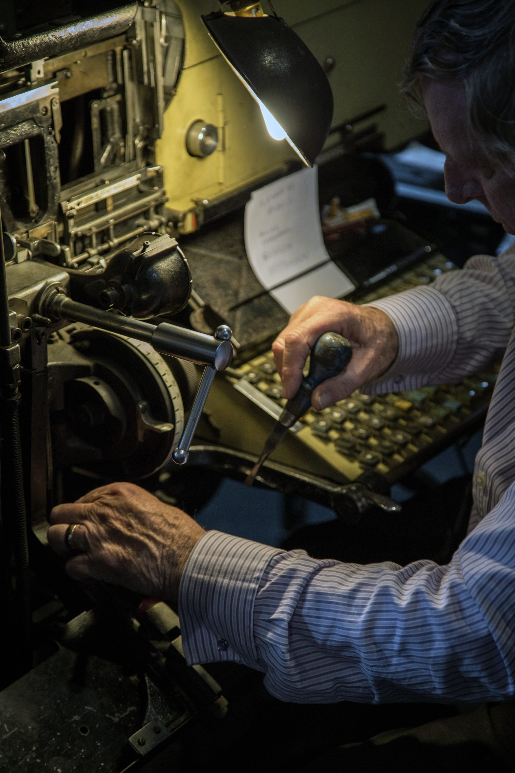 A retired compositor making an adjustment on the linotype machine