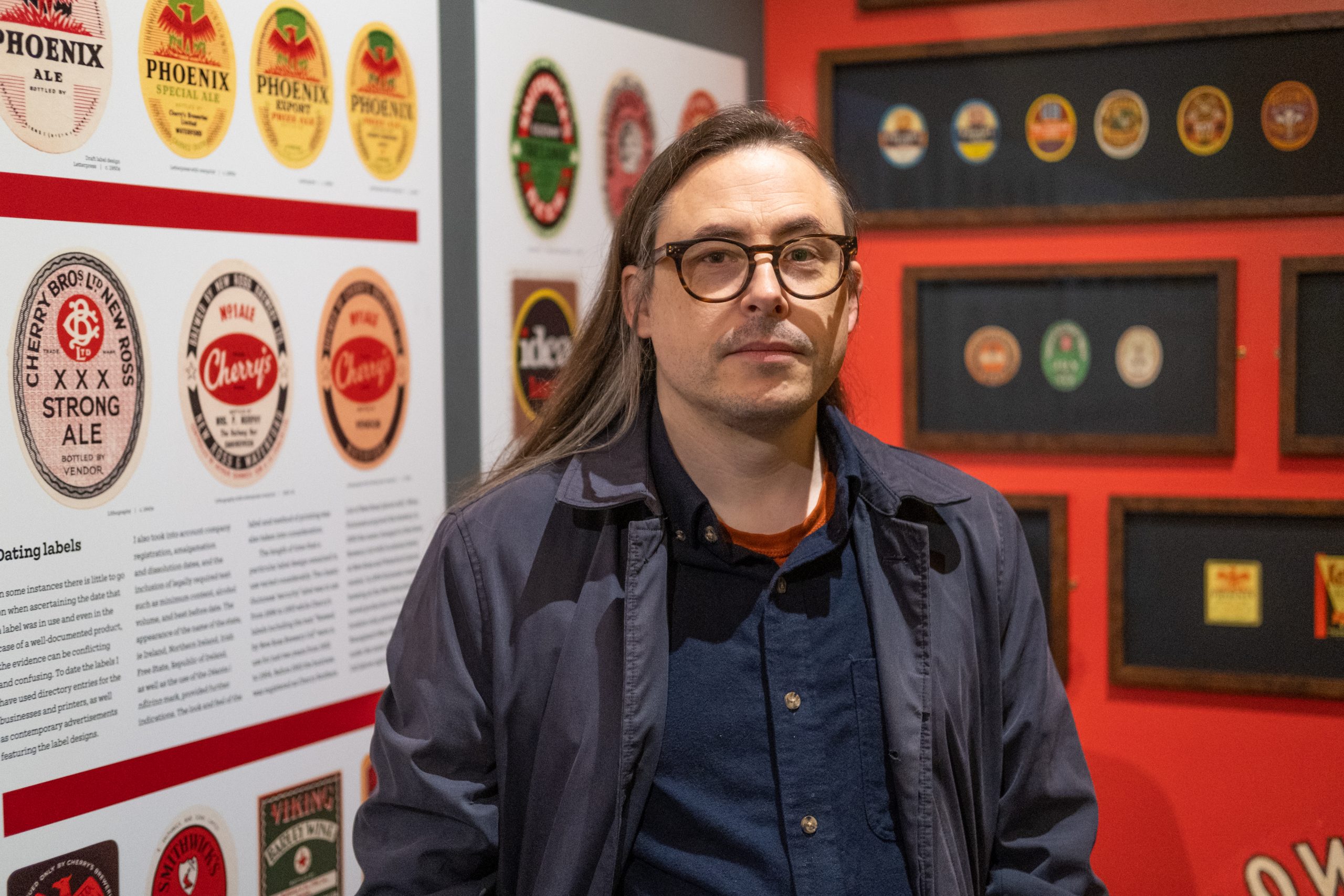 A photo of Niall McCormack, curator, in the exhibition 'Grand Stuff: Label Art from Ireland'.