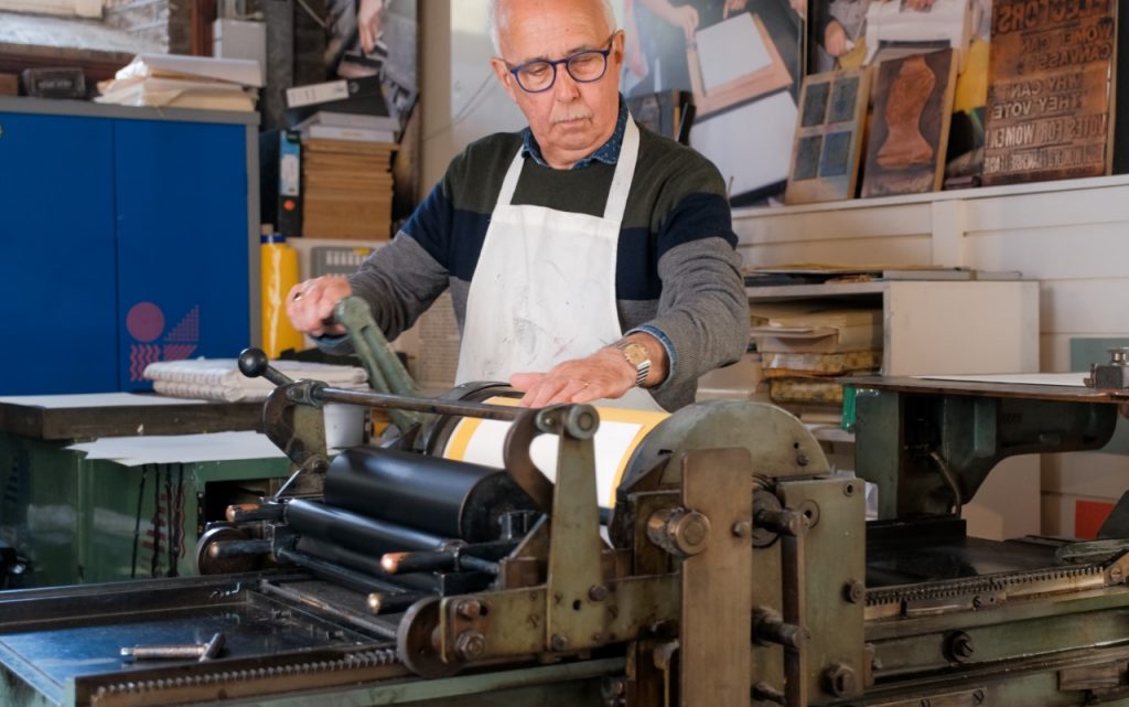 Printer Sean Sills printing a page of Short Stories in Print on the Vandercook press in the National Print Museum
