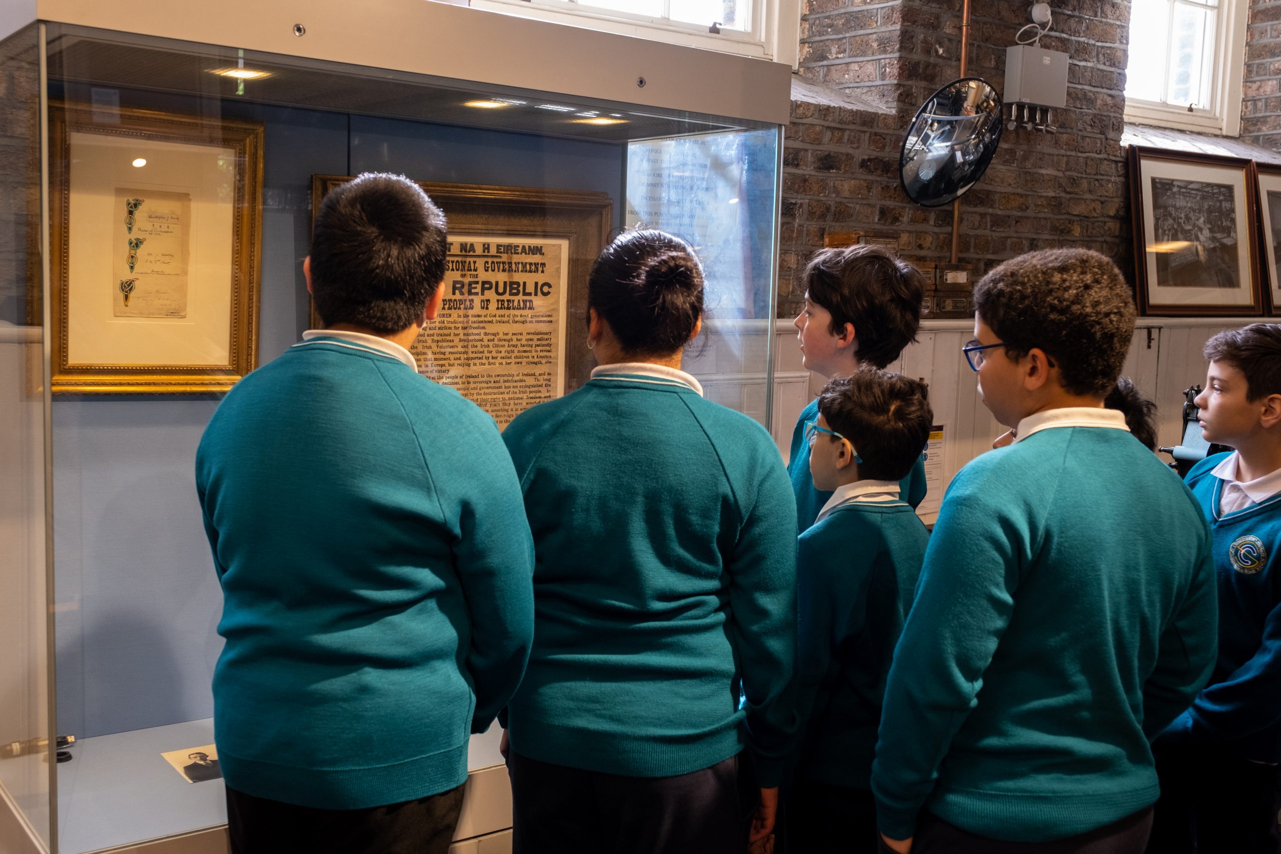 A group of primary school students gather around a display of an original Proclamation