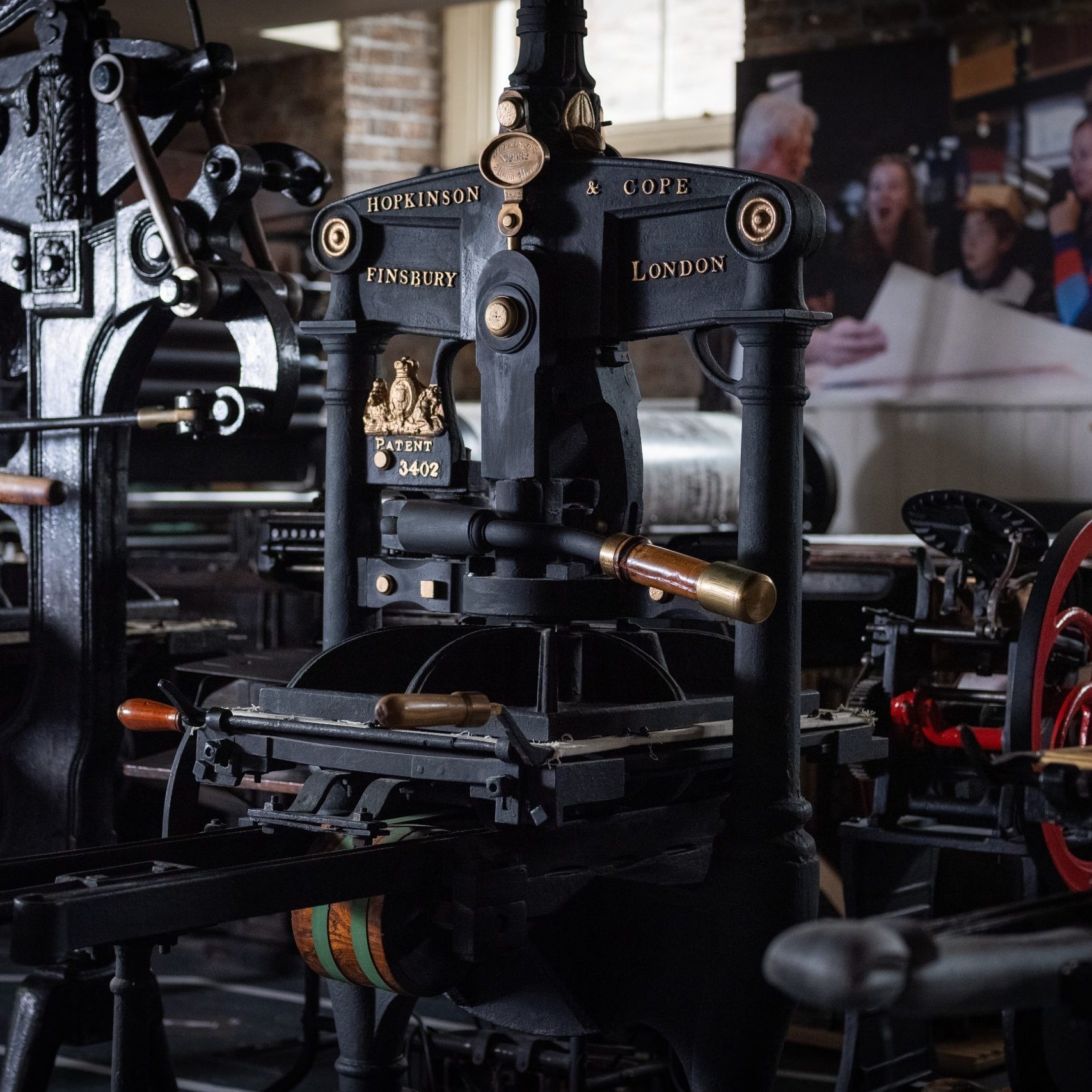An image centered on the black Hopkinson & Cope printing press, flanked by Columbian and Albion presses