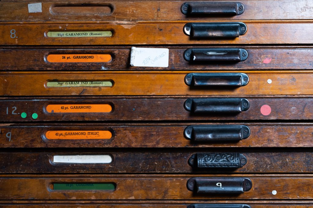 An image of several drawers of type, their handles, and the labels which indicate their font and size