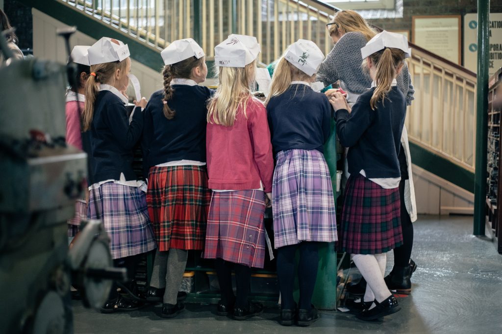 A group of primary school students in kilts standing around the composing stone during a tour