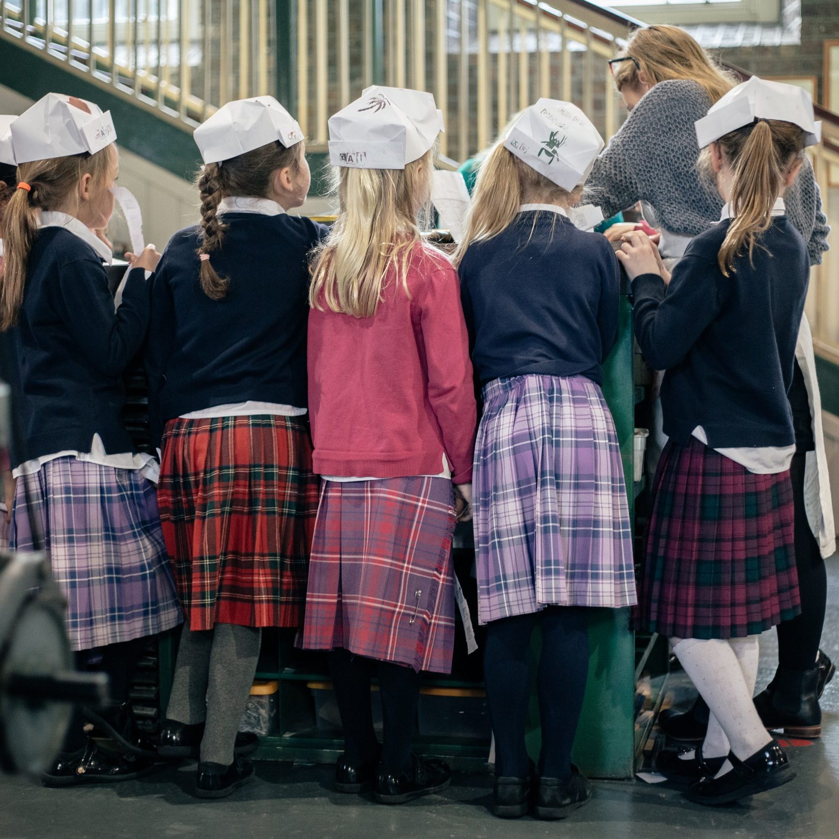 A group of primary school students in kilts standing around the composing stone during a tour