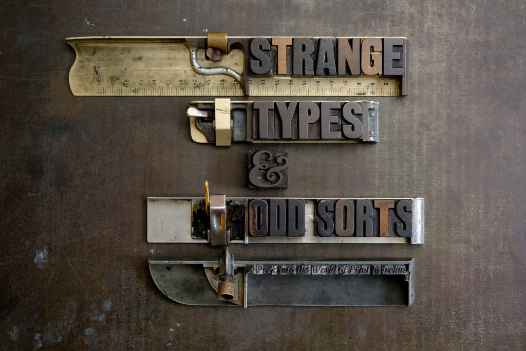 Wooden type spelling out 'Strange Types & Odd Sorts' arranged on composing sticks
