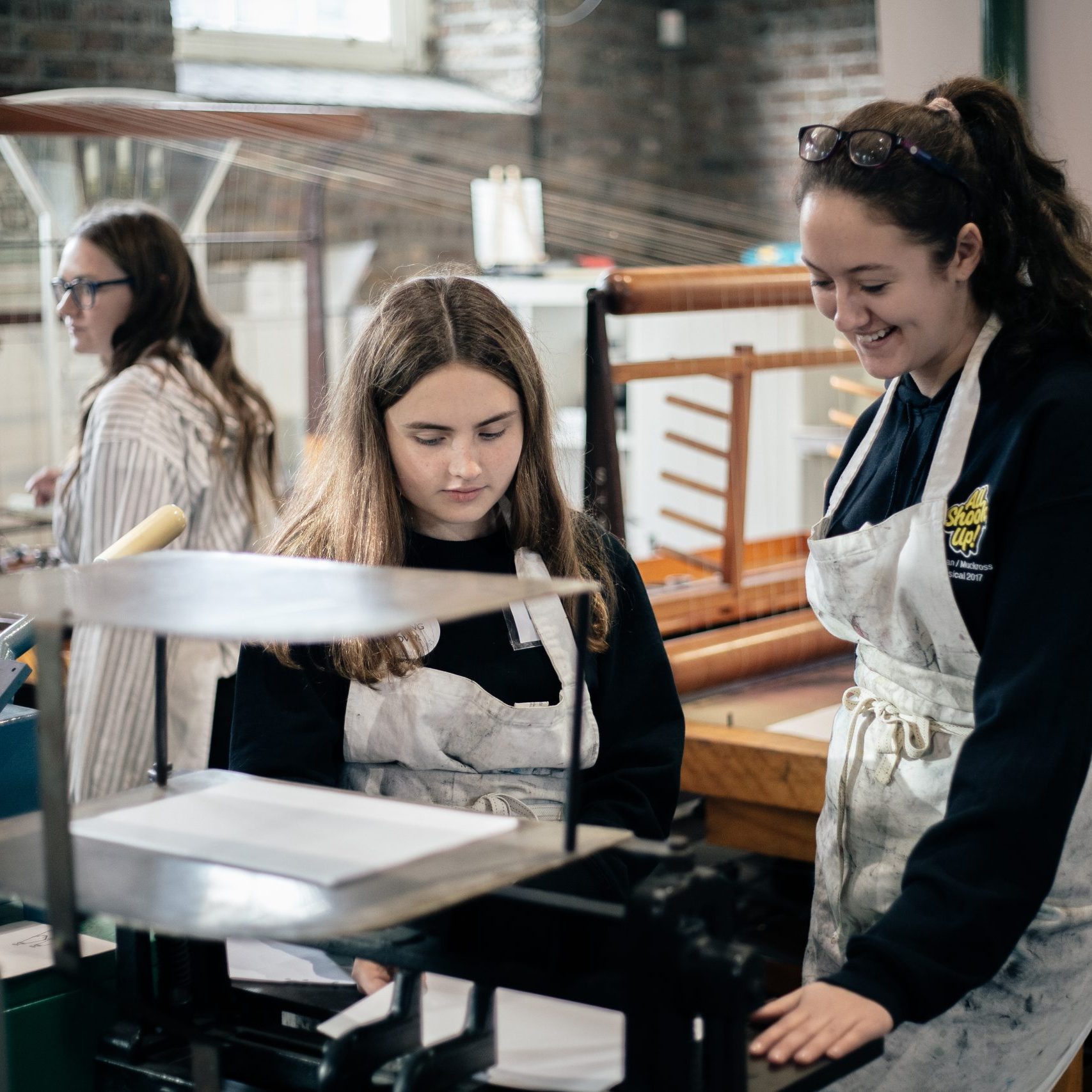 Secondary school students on a tour of the Museum, standing around some of the machines in the finishing area.