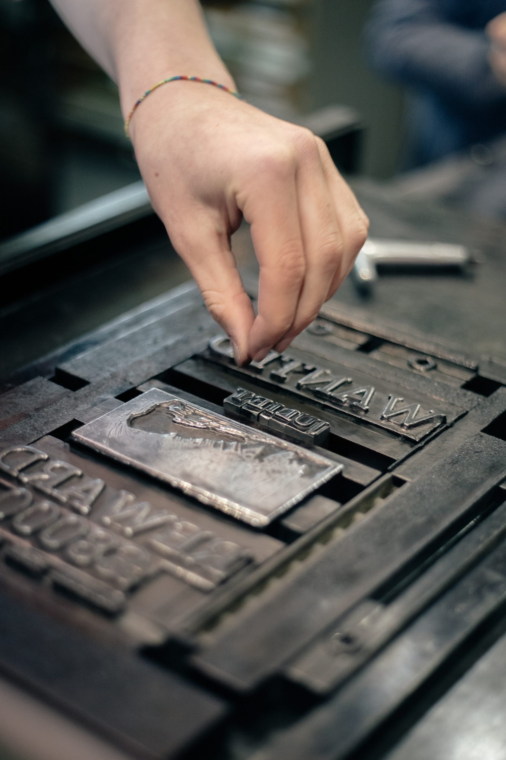 A hand inserting letterpress type into a forme. A hand inserting typeface into a forme.