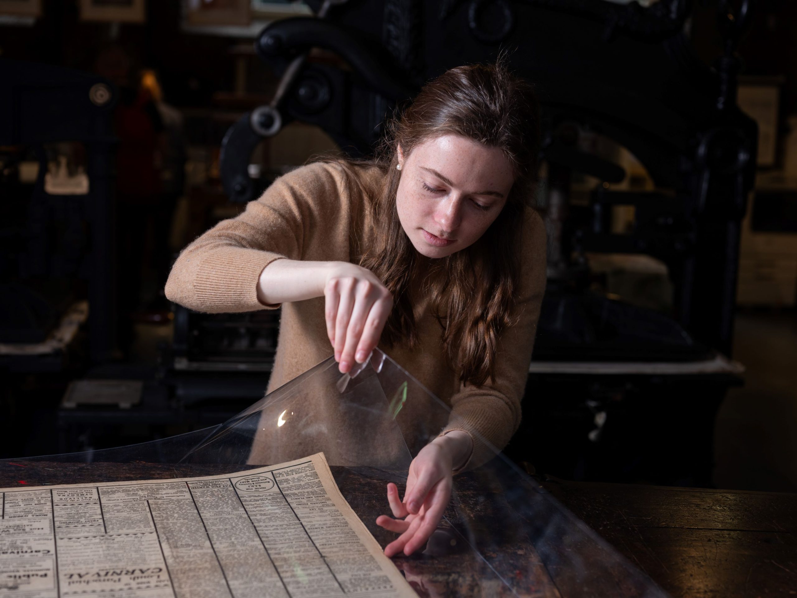 Margaret Aimar inspects a newspaper from the Museum's archive